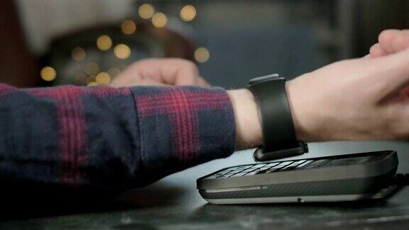 一名男子在咖啡馆用电子智能手表付款非接触式NFC技术网上购物使用现代技术消费主义网上购物男人正在用智能手表支付