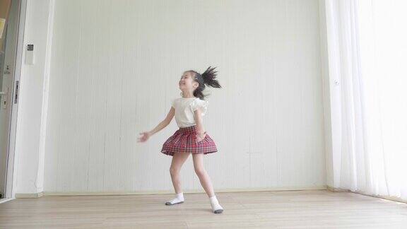 一个穿着白色t恤和迷你裙的小女孩在房间里跳舞她梦想成为一名芭蕾舞演员