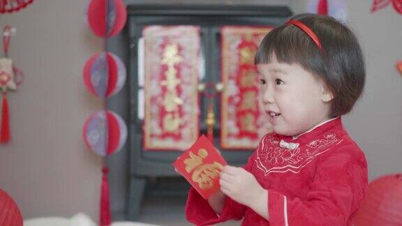 中国一个蹒跚学步的小女孩在家里庆祝春节得到红包