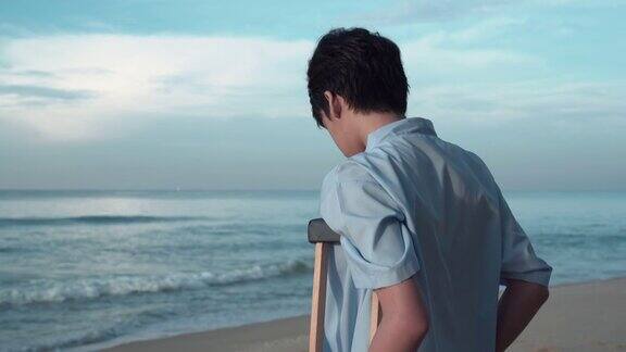 拄着拐杖的年轻病人在海滩上放松拄着拐杖的残疾人在海滩上旅行