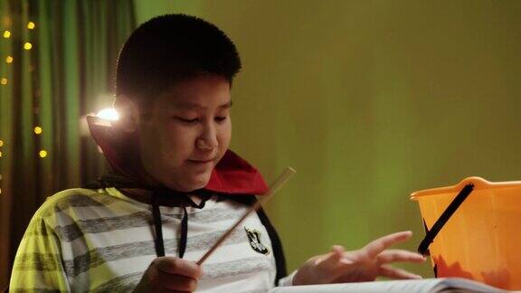 亚洲男孩与魔术棒玩在万圣节在晚上在家里
