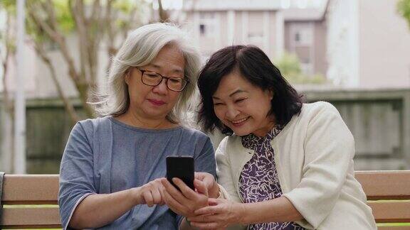 两位资深女性正在智能手机上玩社交媒体