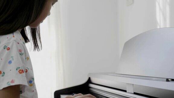 4K:亚洲女孩弹钢琴的慢镜头倾斜拍摄