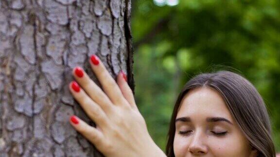 年轻美丽的女子抚摸着树爱着自然感受着和平和团结
