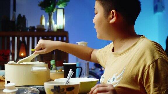 亚洲男孩晚上在家和家人一起吃涮锅涮锅或寿喜烧生活理念