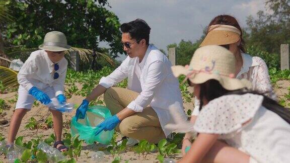 幸福的亚洲家庭带着垃圾袋一起在沙滩上清洁区域