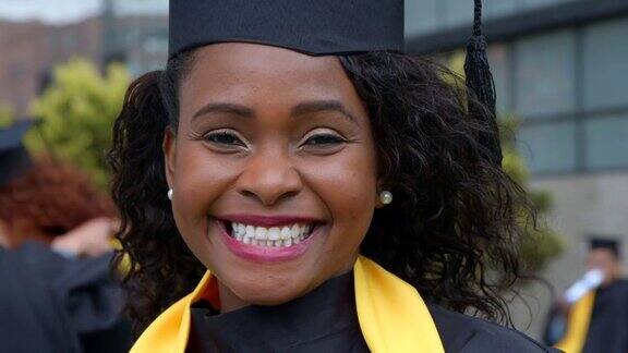 黑色美丽的女性毕业生在大学毕业典礼后面对镜头