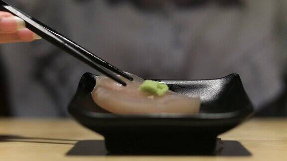 4K:近距离用筷子夹起三文鱼生鱼片日本食物