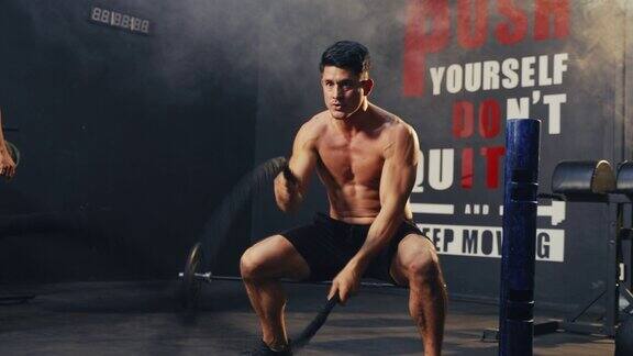 年轻的亚洲男子在健身房用战斗绳进行运动训练力量和动力肌肉锻炼