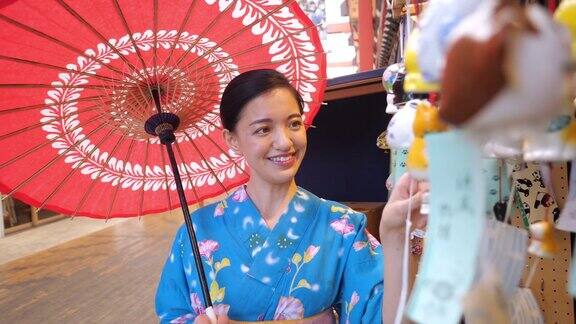 年轻女子在Yukata看日本风铃(风铃)在购物中心