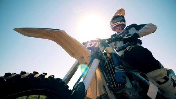 FMX骑手背对着太阳坐在摩托车上