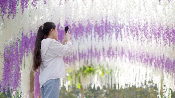 十几岁的女孩在紫藤花树下拍照