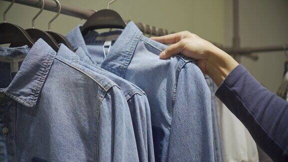 一名男子在服装店的衣架上挑选衣服