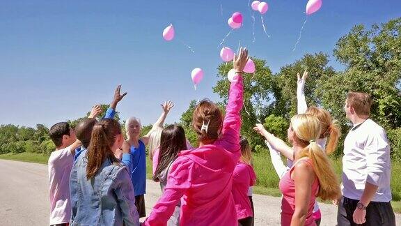 各种各样的人在乳腺癌慈善活动上放飞粉色气球