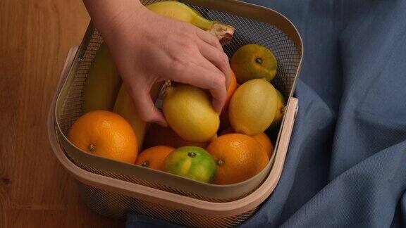 一个女人把手伸进一篮子水果里从里面拿出一个柠檬