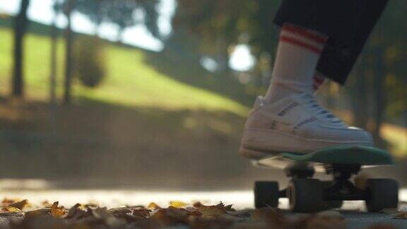 青少年们在公园里的落叶上玩滑板专注于前景缓慢的运动