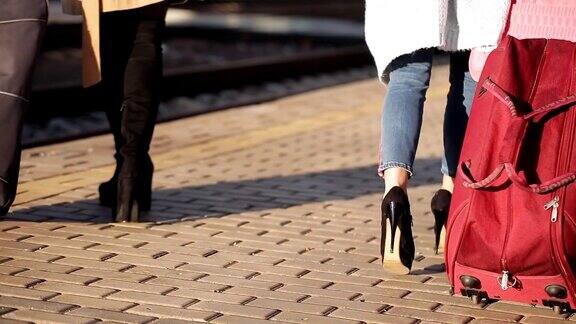 两个女孩在火车站里提着行李箱在站台上等车