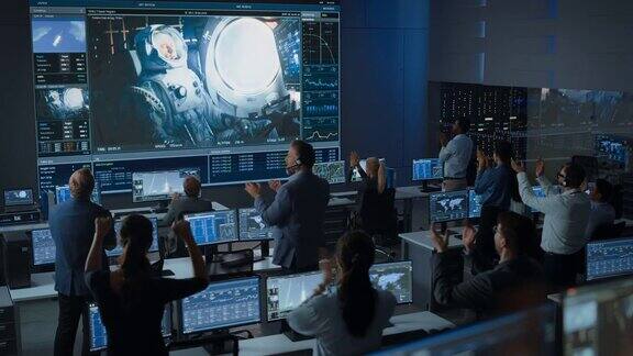 任务控制中心的一群人见证了火箭发射的成功飞行控制人员坐在电脑显示器前监控机组人员的任务队员起立鼓掌