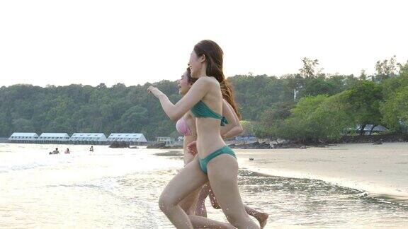 一群快乐的女孩朋友穿着比基尼在海滩上跑步快乐的女人在暑假游客群缓慢的运动