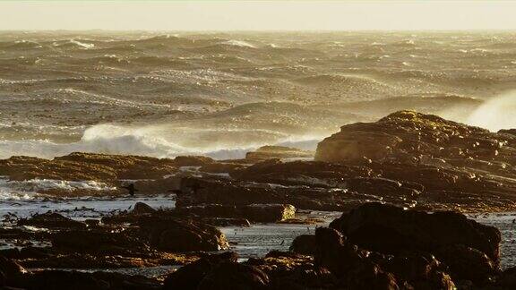暴风雨的海浪打破岩石海岸日落南非