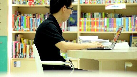 幻灯片镜头学生使用笔记本电脑在图书馆看书