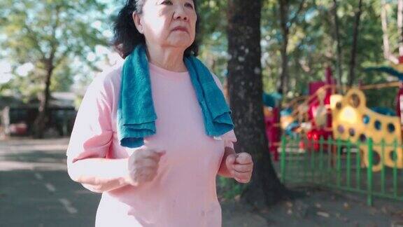 在一个阳光明媚的日子里亚洲老年肥胖女性在公园的跑道上慢动作跑步退休生活方式的活动健康护理动机脉搏血压跟踪前瞻