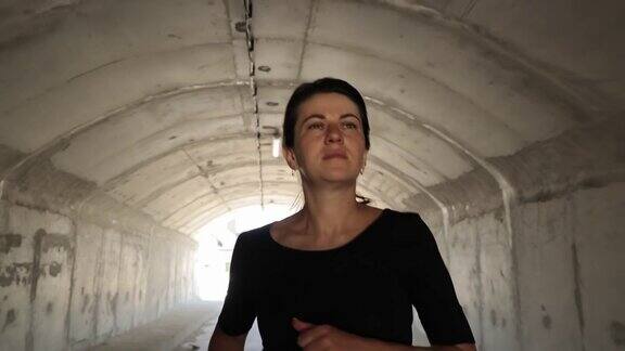 一个女人在隧道里奔向光明运动员在隧道里跑步积极的生活方式