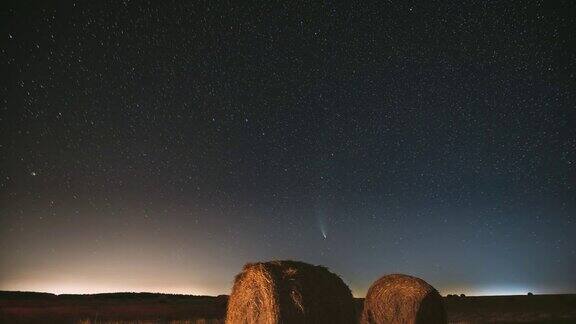 彗星NeowiseC2020F3在夜晚星空在夏季农业领域的草垛上夜晚的星星与收获后的干草捆的乡村景观农业FullHD间隔拍摄