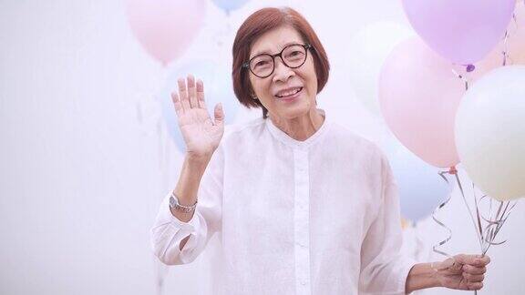 快乐的亚洲资深妇女与气球老年人生日或周年聚会概念