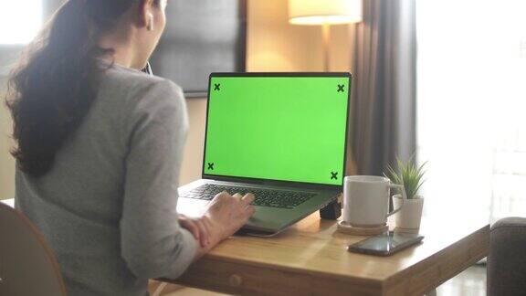 在家里使用绿色屏幕笔记本电脑的妇女