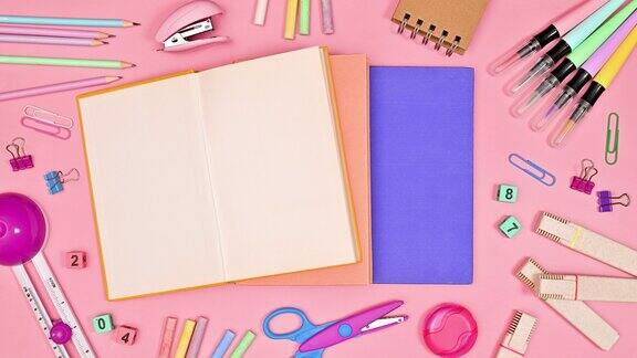 学校文具移动周围的书籍和复制空间打开书籍在粉彩粉红色的背景平的停止运动