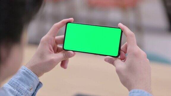 男人看智能手机与绿色色度键屏幕近距离