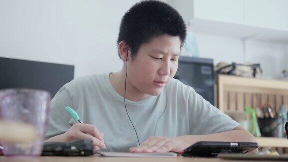 亚洲男孩在COVID-19期间通过智能手机学习在线课程隔离的生活方式概念