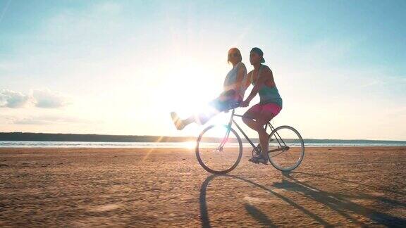 年轻的女人和男人骑着自行车在海边玩慢镜头