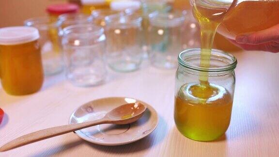 一个女人把蜂蜜倒进白色桌子上的透明罐子里