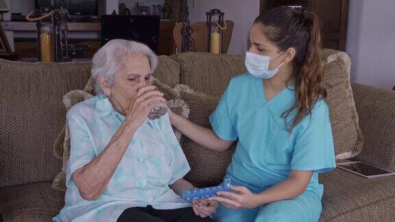 西班牙年轻护士与高级妇女帮助服药期间的家庭访问