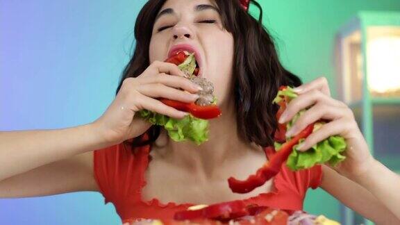 一个饥饿的女孩从一个大汉堡里吃肉排、辣椒和生菜