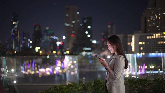 女商人晚上在城市里使用智能手机
