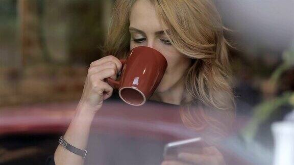 拿着智能手机在咖啡馆喝咖啡的女商人