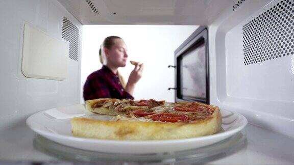 女孩用微波炉加热食物烤披萨放在烤箱里的盘子里