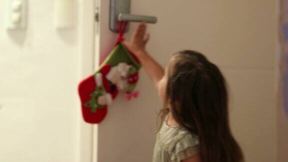 小女孩打开了家的前门等待圣诞老人的到来