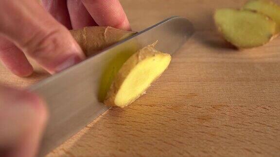 一名男子用刀将多汁的生姜切成块在一块木板上