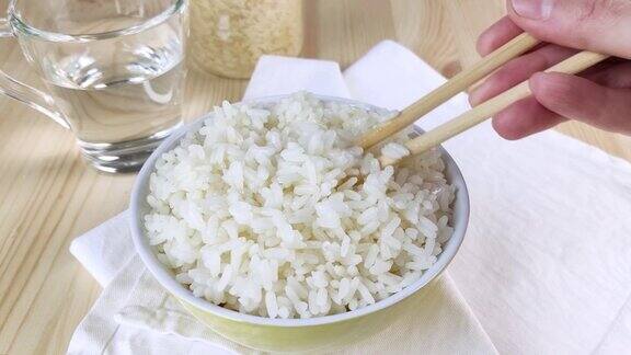 用筷子在圆碗里搅拌白米饭然后端上桌