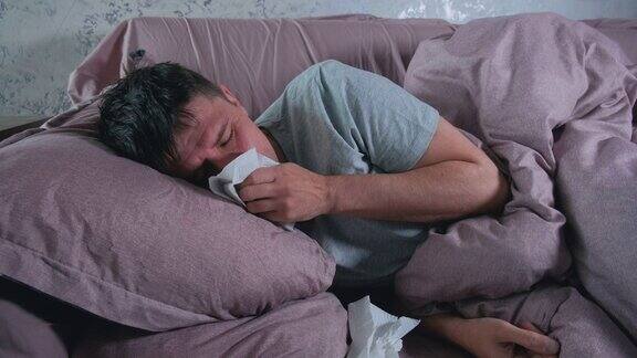 患有感冒、流感或病毒性疾病的病人躺在床上使用纸巾