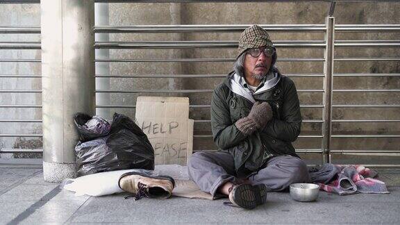 无家可归的老人坐在人行道上