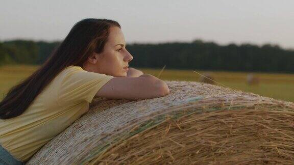 一个年轻的女人靠在一捆干草上闭上了眼睛