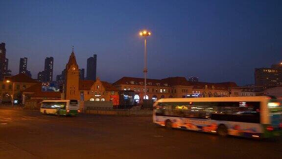 黄昏夜晚灯火辉煌的青岛市著名的火车站交通街道广场全景4k中国