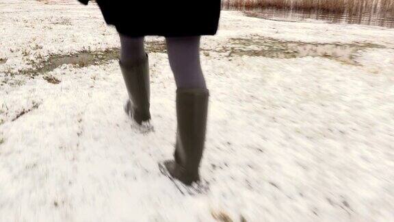 冬天穿着胶靴在雪地上行走的女人