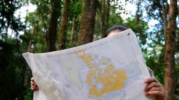 年轻女子旅行者与地图和背包放松在夏季假期的森林户外徒步旅行生活方式