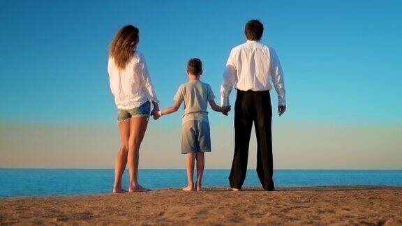 妈妈爸爸和儿子站在海滩上望着远方